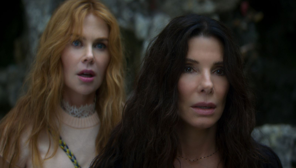 Nicole Kidman and Sandra Bullock look forward in shock in a still from the movie Practical Magic 2.